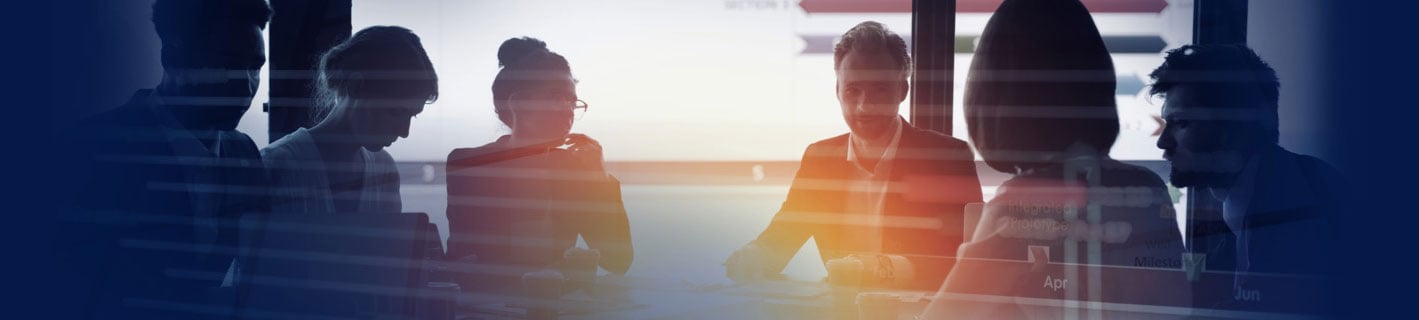 Um einen Tisch sitzende Menschen bei einer Besprechung in einem sonnigen Großraumbüro