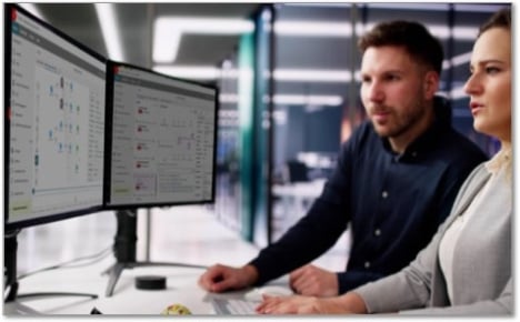 co-workers looking at threat detection screens on a monitor