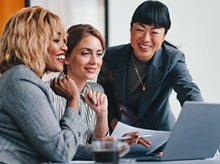 3 women gathered around a laptop