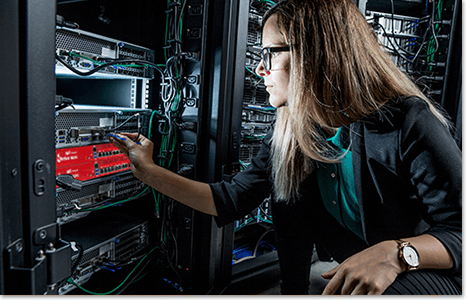 Blonde woman reaching for a red WatchGuard Firebox in a server rack